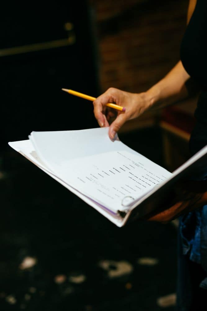 Closeup of a person’s hands holding a binder and a pencil, preparing to mark up documents.